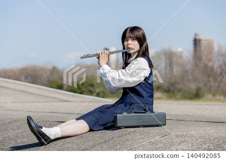 A high school girl playing the flute under the blue sky. A high school girl playing the flute under the blue sky. 140492085