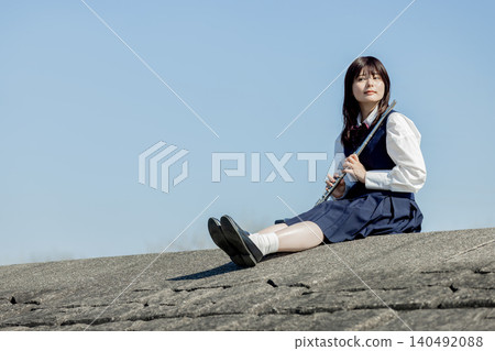 A high school girl playing the flute under the blue sky. A high school girl playing the flute under the blue sky. 140492088