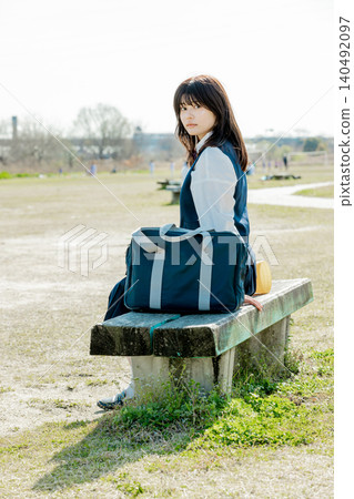 A high school girl sitting on a bench turns around. A high school girl sitting on a bench turns around. 140492097