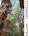 Child sitting inside mesh tunnel in forest adventure park 140492113