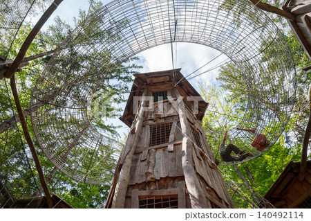 Wooden tower and mesh tunnels in forest adventure park 140492114