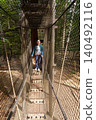 Child exploring rope tunnel in forest adventure park 140492116