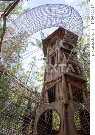Wooden tower and mesh tunnels in forest adventure park 140492117