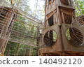 Wooden tower and mesh tunnels in forest adventure park 140492120