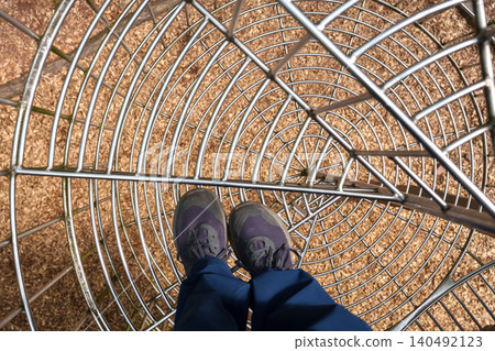 Point of view inside metal mesh tunnel at adventure park 140492123