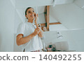 Cheerful young Caucasian woman applying cosmetic serum during bathroom morning routine 140492255