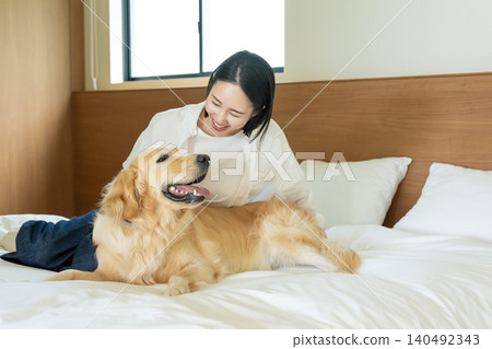 一位女士和她的狗在臥室的床上微笑。 一位女士和她的狗在臥室的床上微笑。 140492343