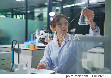 Scientist Conducting Research with Liquid Sample in Laboratory Scientist Conducting Research with Liquid Sample in Laboratory 140492512