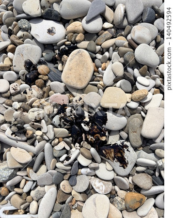 Coastal pebbles smeared with black fuel oil or drops of oil. Pollution of nature Coastal pebbles smeared with black fuel oil or drops of oil. Pollution of nature 140492594