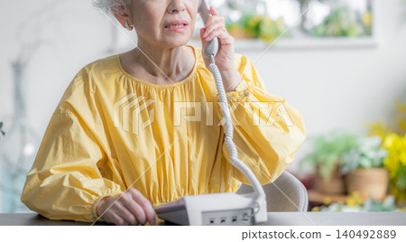 一位老婦人正在用座機打電話。 140492889