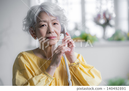 一位老婦人正在用座機打電話。 140492891