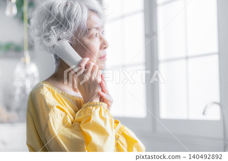 A senior woman making a phone call on a landline. A senior woman making a phone call on a landline. 140492892