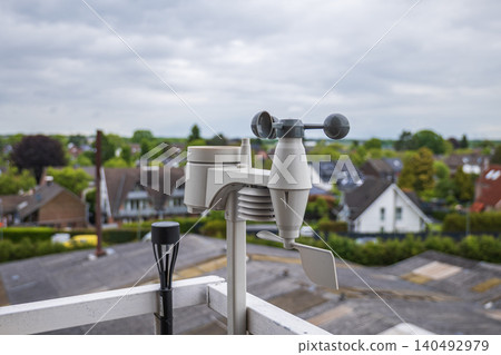 Home weather station anemometer on balcony railing measuring wind speed and direction with suburban background Home weather station anemometer on balcony railing measuring wind speed and direction with suburban background 140492979