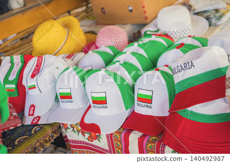 Bulgaria hats and caps with flag colors are displayed for sale at outdoor market souvenir stand. Bulgaria souvenir merchandise supports travel, tourism, national identity, retail shopping 140492987