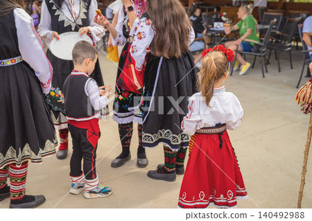 Children and women wear folk costumes during Rose Festival in Kazanlak, Bulgaria outdoors. Folk costume scene represents heritage, culture, celebration, family event Children and women wear folk costumes during Rose Festival in Kazanlak, Bulgaria outdoors. Folk costume scene represents heritage, culture, celebration, family event 140492988