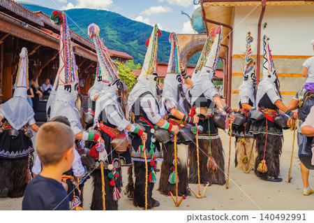 Kukeri performers in traditional costumes, masks, bells and costumes walk in a group during the Rose Festival in Kazanlak, Bulgaria Kukeri performers in traditional costumes, masks, bells and costumes walk in a group during the Rose Festival in Kazanlak, Bulgaria 140492991
