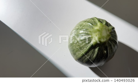 Round zucchini on a white table bathed in natural light. Round zucchini on a white table bathed in natural light. 140493026