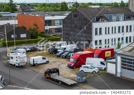 Neuss, Germany, 10.06.2026 - High angle view of a commercial parking lot with delivery vans, trucks, tow truck and motorhomes near an office building in a European industrial area Neuss, Germany, 10.06.2026 - High angle view of a commercial parking lot with delivery vans, trucks, tow truck and motorhomes near an office building in a European industrial area 140493272
