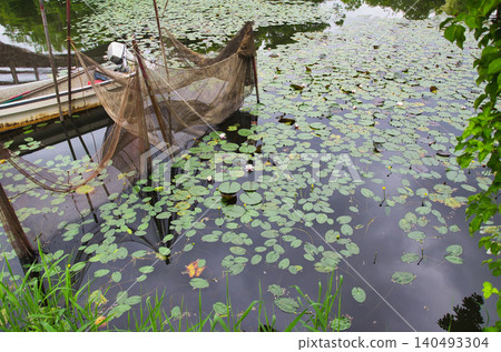 A lakeside landscape depicted by fishing gear and lotus flowers. A lakeside landscape depicted by fishing gear and lotus flowers. 140493304