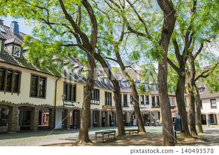 Germany old town square with traditional half timbered houses and green trees, historic european city street view in summer, charming architecture of ancient village plaza Germany old town square with traditional half timbered houses and green trees, historic european city street view in summer, charming architecture of ancient village plaza 140493578
