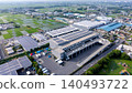 [Aerial view] Large-scale logistics center with solar panels installed and suburban scenery 140493722