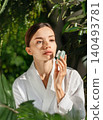 Young Caucasian woman using silicon facial cleansing brush in bright green bathroom 140493781