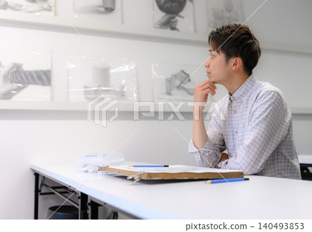 A male student's profile as he contemplates drawing in the classroom. 140493853