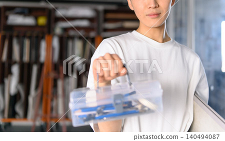 一名學生拿著美術用品盒和畫筆。 140494087