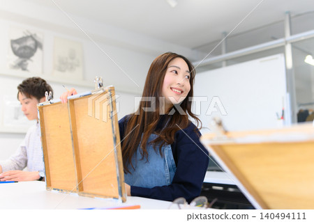 A female student smiling while creating art at an art preparatory school. 140494111
