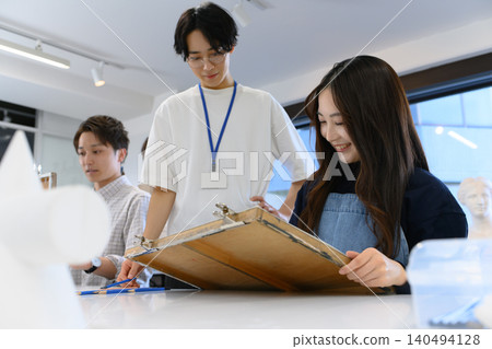 A female student drawing under the guidance of an instructor. 140494128