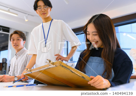 一位微笑的女學生正在接受繪畫指導。 140494139
