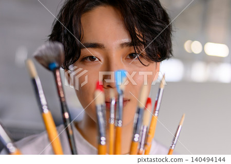 Art students gaze through their paintbrushes, their concentration on their work. Art students gaze through their paintbrushes, their concentration on their work. 140494144