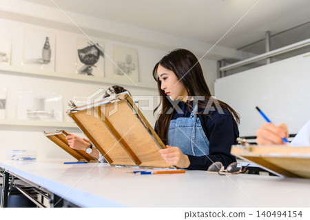 一位女士在藝術預科學校專心致志地畫畫。 一位女士在藝術預科學校專心致志地畫畫。 140494154