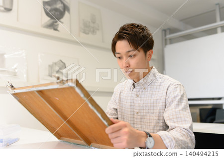 一名男子正在藝術預科學校創作他的作品。 140494215