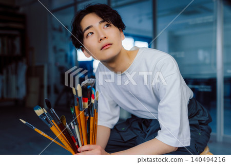 A man holding a brush, gazing into the distance. A man holding a brush, gazing into the distance. 140494216