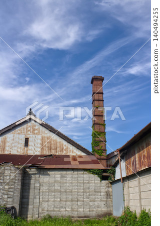 In Gojo City, Nara Prefecture, the brick chimney and weathered factory building of a historic sake brewery stand out against the blue sky. In Gojo City, Nara Prefecture, the brick chimney and weathered factory building of a historic sake brewery stand out against the blue sky. 140494255