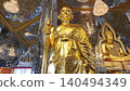 UTHAI THANI, THAILAND - MAY 2, 2025. A golden statue of a revered Buddhist monk (Luang Phor Ruesi Lingdam) sits inside the famous Mirrored Crystal Sanctuary (Prasat Thong Kham) at Wat Tha Sung temple  140494349
