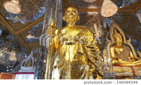 UTHAI THANI, THAILAND - MAY 2, 2025. A golden statue of a revered Buddhist monk (Luang Phor Ruesi Lingdam) sits inside the famous Mirrored Crystal Sanctuary (Prasat Thong Kham) at Wat Tha Sung temple UTHAI THANI, THAILAND - MAY 2, 2025. A golden statue of a revered Buddhist monk (Luang Phor Ruesi Lingdam) sits inside the famous Mirrored Crystal Sanctuary (Prasat Thong Kham) at Wat Tha Sung temple 140494349