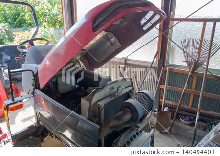 Open the hood of the tractor for maintenance. 140494401