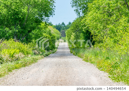 A straight, unpaved road (dirt road image) with foreground and background blur. 140494654