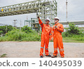 Two engineers standing and pointing during oil refinery inspection outdoors 140495039