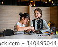 Focused student assembles robotic hand under teacher guidance in interactive STEM session 140495044