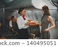 Flight attendant welcoming professional female passenger in premium business class cabin 140495051