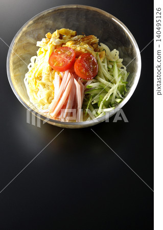 A single serving of chilled ramen in a clear glass bowl, photographed against a black background. A single serving of chilled ramen in a clear glass bowl, photographed against a black background. 140495126