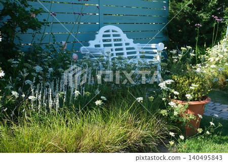 A white bench and white flowers in a stylish garden A white bench and white flowers in a stylish garden 140495843