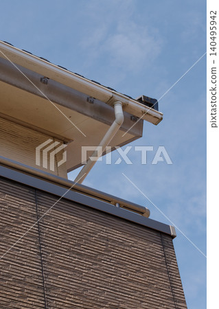 The eaves and siding of the detached house show noticeable signs of fading and staining. 140495942