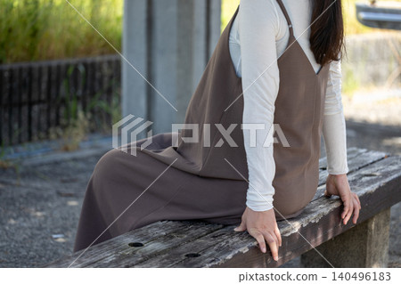 A pregnant woman in her final month of pregnancy resting on a bench in the shade. A pregnant woman in her final month of pregnancy resting on a bench in the shade. 140496183