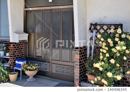 A sliding entrance door, wainscoting tiles, and roses in a Japanese house from the Showa era. A sliding entrance door, wainscoting tiles, and roses in a Japanese house from the Showa era. 140496345