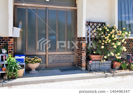 A sliding entrance door, wainscoting tiles, and roses in a Japanese house from the Showa era. A sliding entrance door, wainscoting tiles, and roses in a Japanese house from the Showa era. 140496347