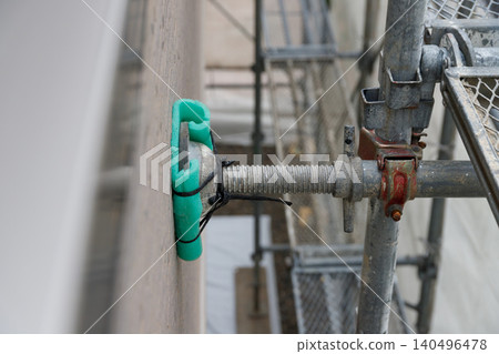 Close-up of scaffolding and protective coverings used during exterior wall painting. 140496478